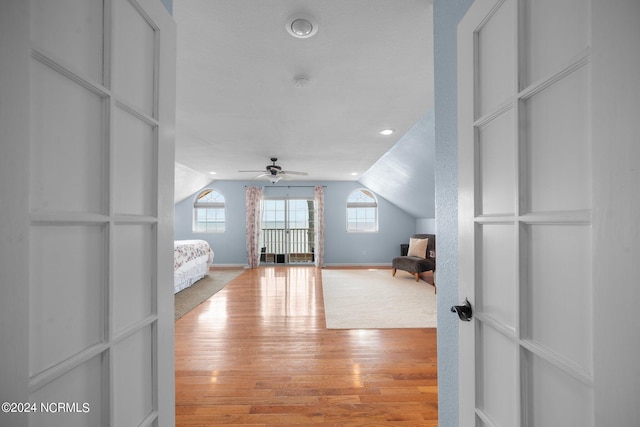 unfurnished bedroom with lofted ceiling, baseboards, multiple windows, and light wood finished floors