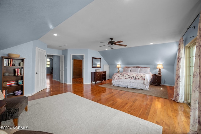 bedroom featuring lofted ceiling, multiple windows, light wood-type flooring, and ceiling fan