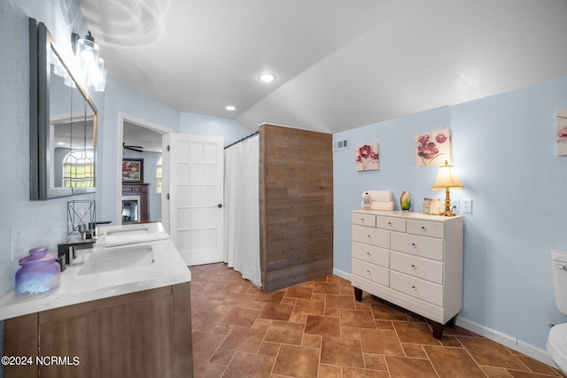 bathroom featuring dual vanity, tile patterned floors, lofted ceiling, and toilet