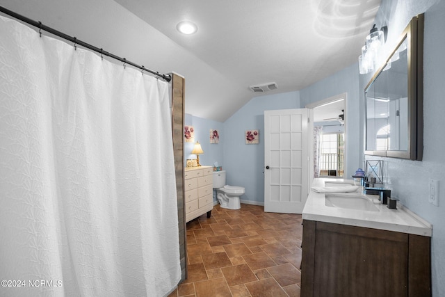 bathroom featuring toilet, ceiling fan, dual vanity, tile patterned floors, and vaulted ceiling