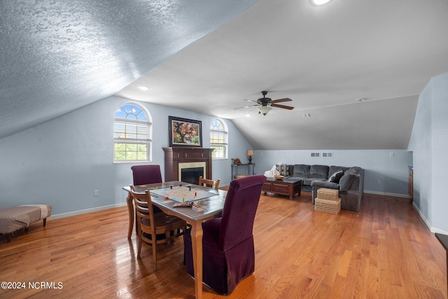 dining area featuring a textured ceiling, light hardwood / wood-style flooring, lofted ceiling, and ceiling fan