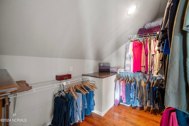 walk in closet with vaulted ceiling and light hardwood / wood-style flooring