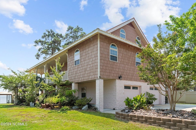 view of home's exterior featuring a balcony, a garage, and a lawn