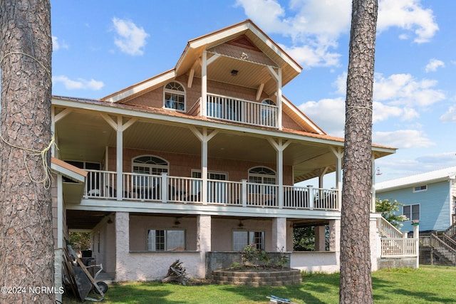 back of property with a balcony, a yard, metal roof, and stucco siding