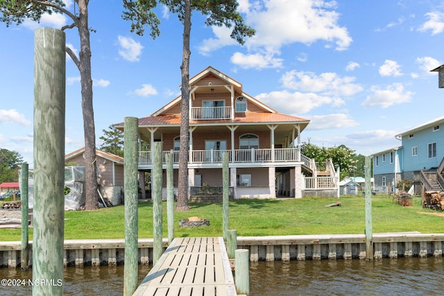 back of house with a balcony, a water view, and a yard