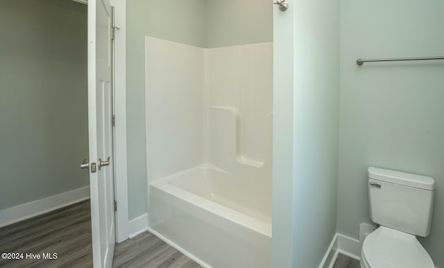 bathroom with shower / bathing tub combination, hardwood / wood-style floors, and toilet