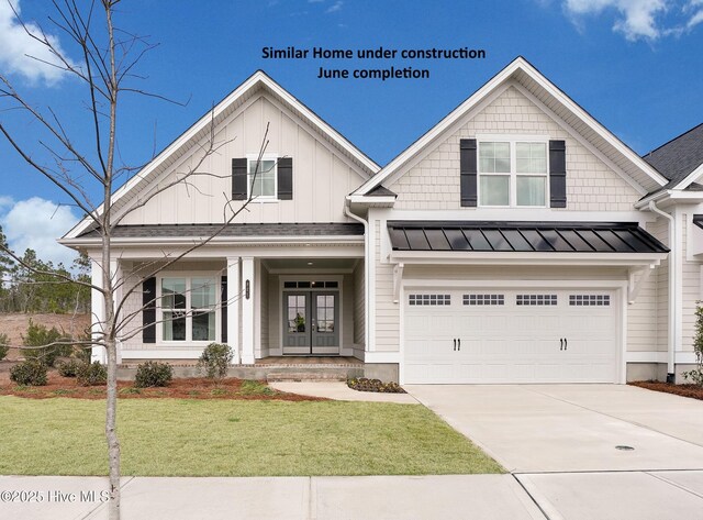 view of front of house with a porch, a garage, french doors, and a front lawn