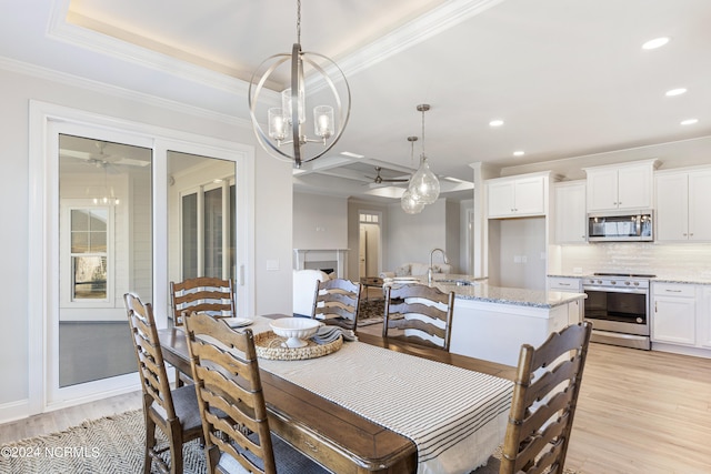 dining space with a tray ceiling, light wood finished floors, a fireplace, and recessed lighting