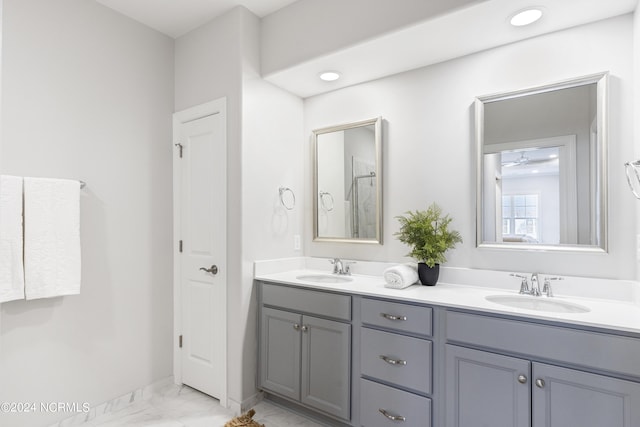 full bath featuring double vanity, marble finish floor, a sink, and recessed lighting