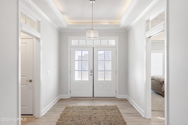 doorway featuring light wood-style floors, a tray ceiling, and baseboards