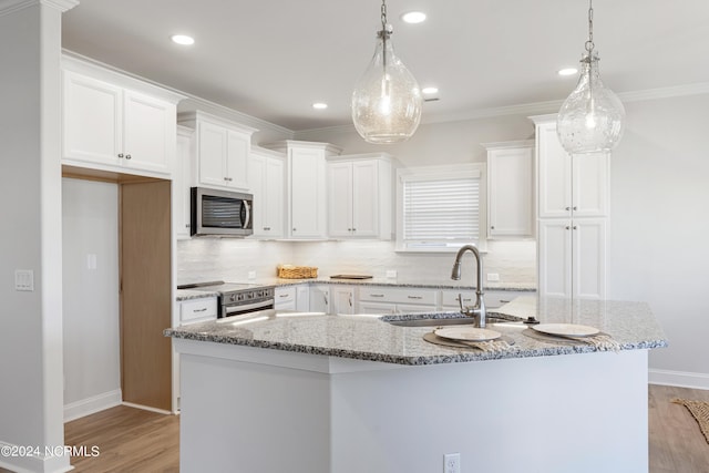 kitchen featuring stainless steel appliances, light wood-style flooring, ornamental molding, white cabinetry, and a sink