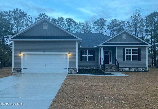 view of front facade featuring driveway, an attached garage, a front yard, and a shingled roof