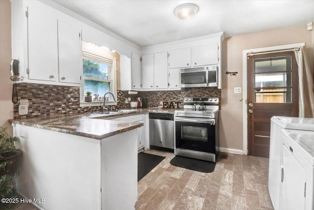 212 Bunche Dr, Goldsboro, NC 27530 - kitchen with stainless steel appliances, separate washer and dryer, decorative backsplash, white cabinetry, and a peninsula
