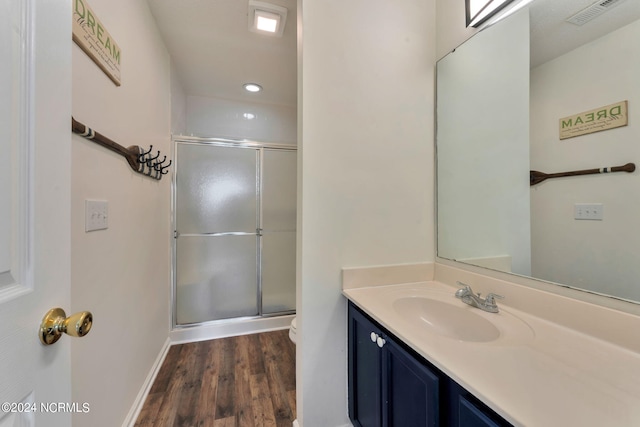 bathroom with a shower with shower door, toilet, wood-type flooring, and vanity