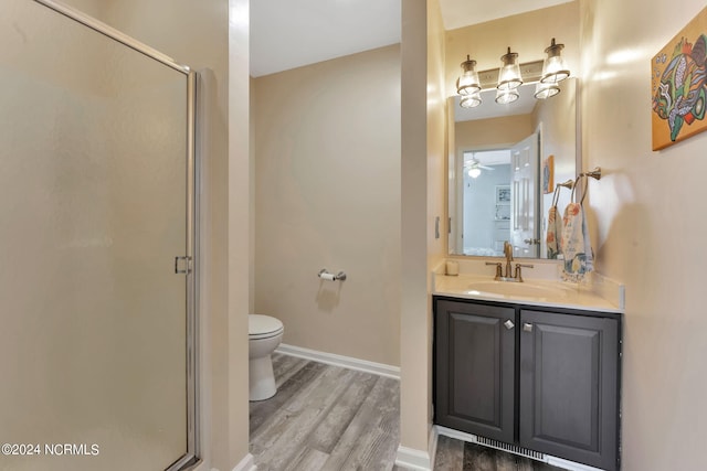 bathroom featuring hardwood / wood-style floors, vanity, ceiling fan, toilet, and a shower with shower door