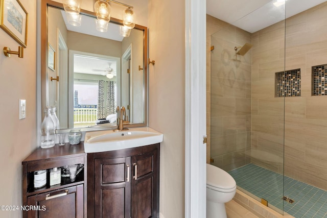 bathroom with vanity, toilet, a shower with door, and ceiling fan