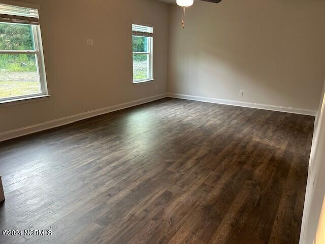 spare room featuring dark wood-type flooring and ceiling fan