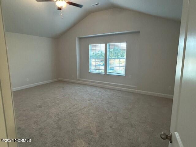 carpeted empty room with ceiling fan and vaulted ceiling