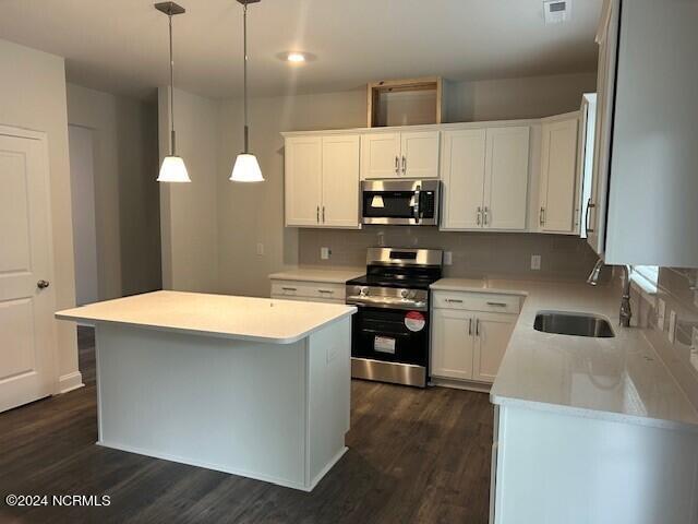 kitchen with a kitchen island, white cabinets, hanging light fixtures, and stainless steel appliances