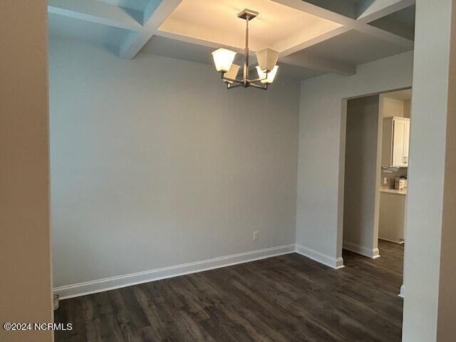 empty room featuring beamed ceiling, dark hardwood / wood-style floors, a notable chandelier, and coffered ceiling