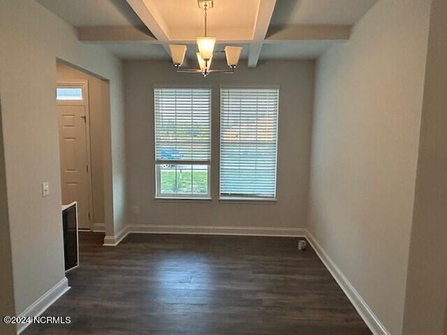 unfurnished dining area with beamed ceiling, coffered ceiling, an inviting chandelier, and dark hardwood / wood-style floors