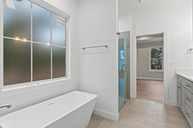 bathroom with a freestanding tub, baseboards, vanity, and a shower stall