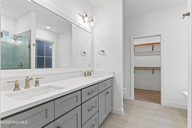 full bath featuring double vanity, a sink, a walk in closet, and a shower stall