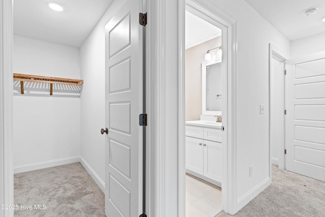 walk in closet with light carpet and a sink