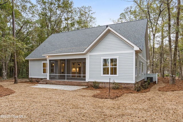 rear view of house featuring a shingled roof and a sunroom