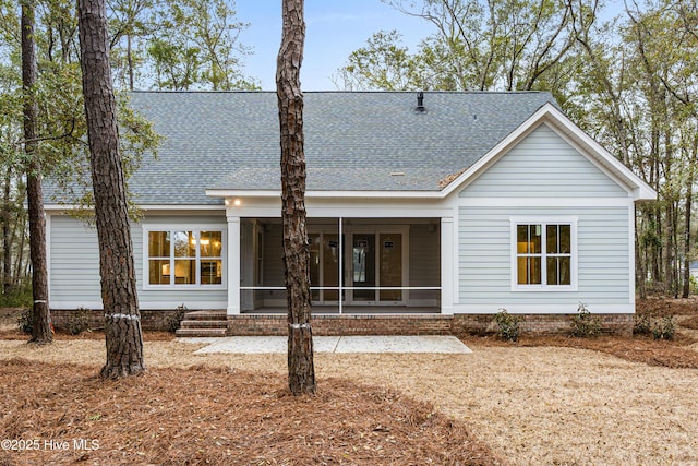 back of property with a shingled roof and a sunroom