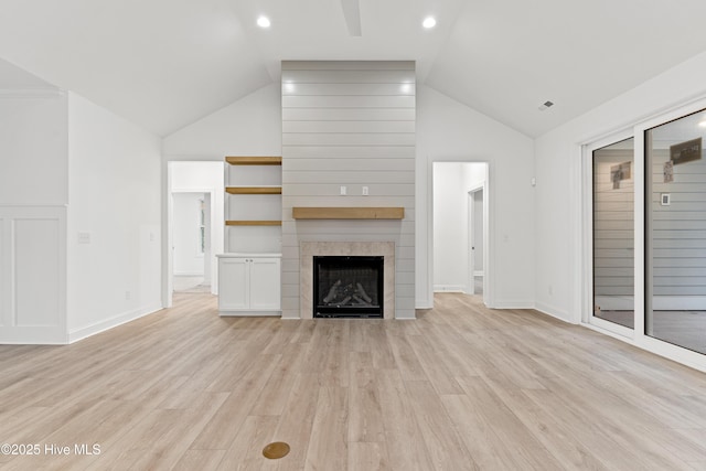 unfurnished living room with light wood-style flooring, a fireplace, visible vents, baseboards, and vaulted ceiling