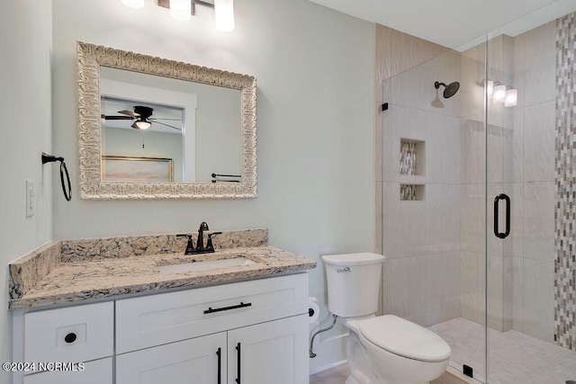 bathroom with ceiling fan, vanity, toilet, and a shower with door