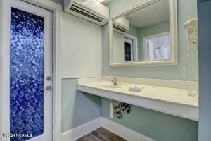 bathroom featuring an AC wall unit, a wall mounted AC, wood finished floors, and baseboards