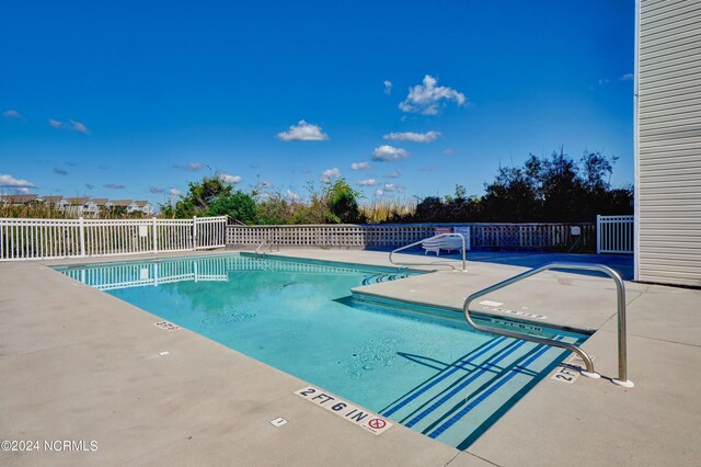 community pool with a patio and fence