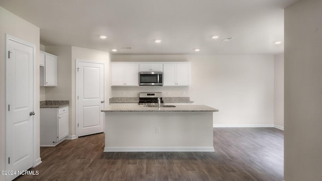 kitchen with white cabinetry, a center island with sink, light stone countertops, and appliances with stainless steel finishes