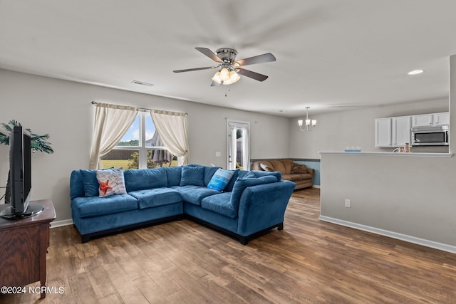 living room with ceiling fan with notable chandelier and hardwood / wood-style floors