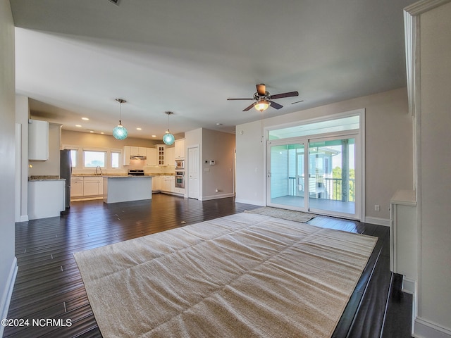 unfurnished living room featuring sink, wood-type flooring, a healthy amount of sunlight, and ceiling fan