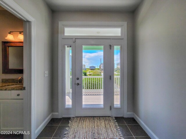 doorway featuring sink and dark tile patterned flooring