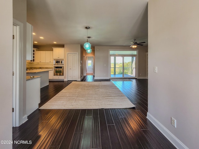 kitchen with appliances with stainless steel finishes, white cabinets, decorative light fixtures, dark hardwood / wood-style floors, and ceiling fan