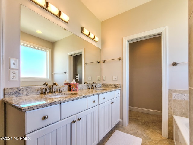 bathroom with a relaxing tiled tub, double sink vanity, and tile patterned flooring