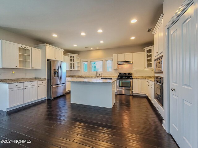 kitchen with dark hardwood / wood-style floors, stainless steel appliances, a center island, and white cabinets