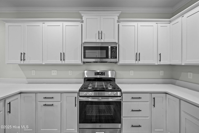 kitchen featuring white cabinets, appliances with stainless steel finishes, and ornamental molding