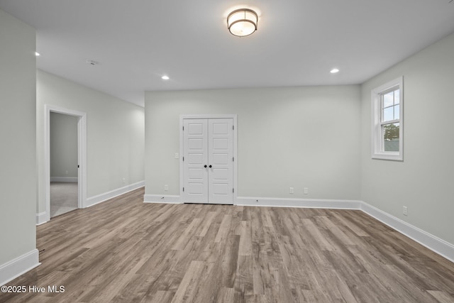 empty room with recessed lighting, wood finished floors, and baseboards