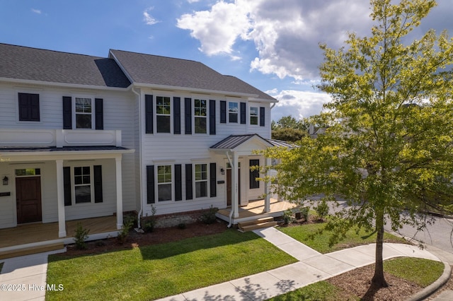 view of front facade featuring covered porch, a front lawn, and a shingled roof