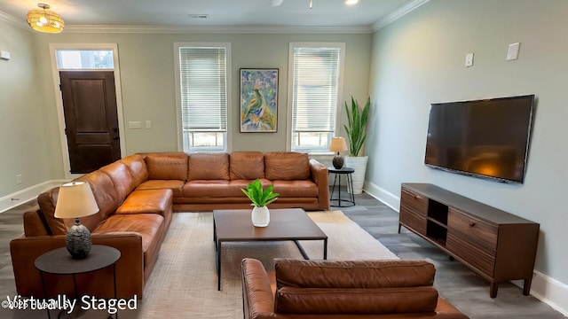 living room with visible vents, baseboards, wood finished floors, and crown molding