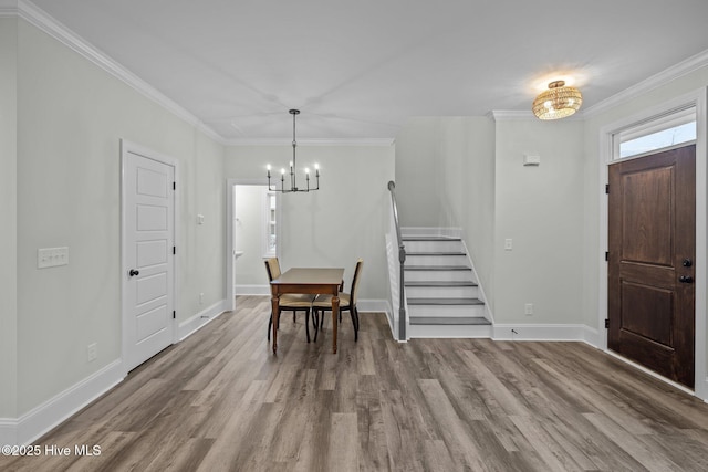 foyer featuring a notable chandelier, wood finished floors, stairs, and crown molding