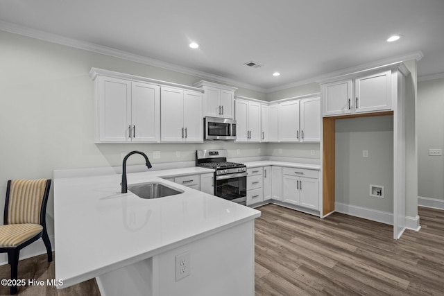 kitchen with visible vents, a sink, dark wood finished floors, appliances with stainless steel finishes, and a peninsula