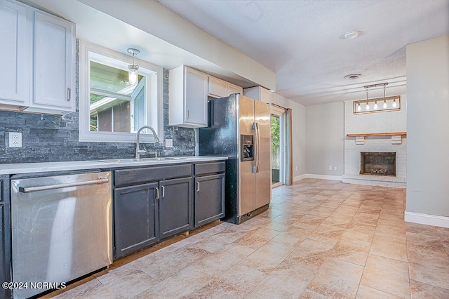 kitchen featuring decorative light fixtures, a fireplace, decorative backsplash, and stainless steel appliances