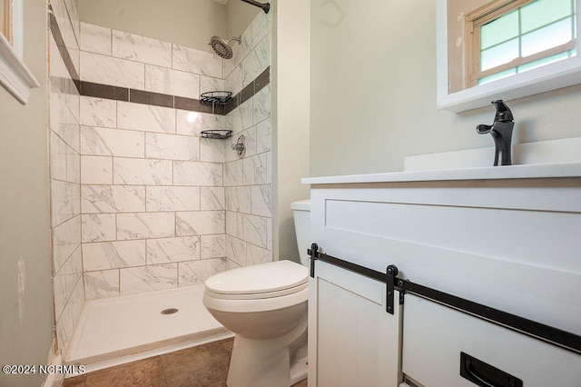 bathroom featuring tile patterned floors, toilet, vanity, and a tile shower