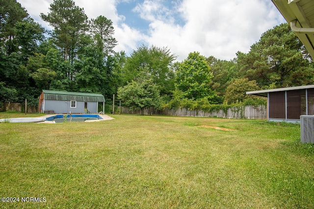 view of yard featuring cooling unit, an outbuilding, a sunroom, and a fenced in pool